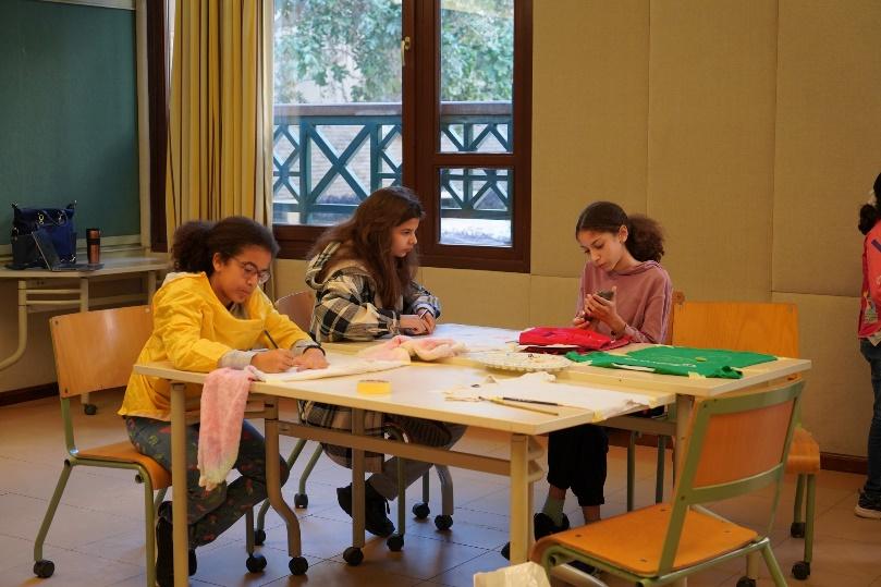 Three girls are sitting and working at a table 