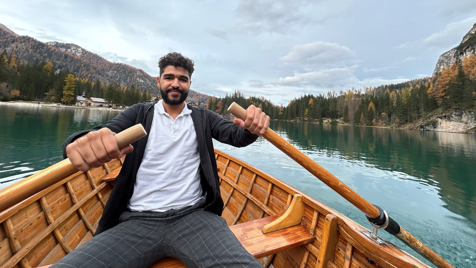 Ahmed Ayman sits in a row boat in beautiful Italian lake scenery