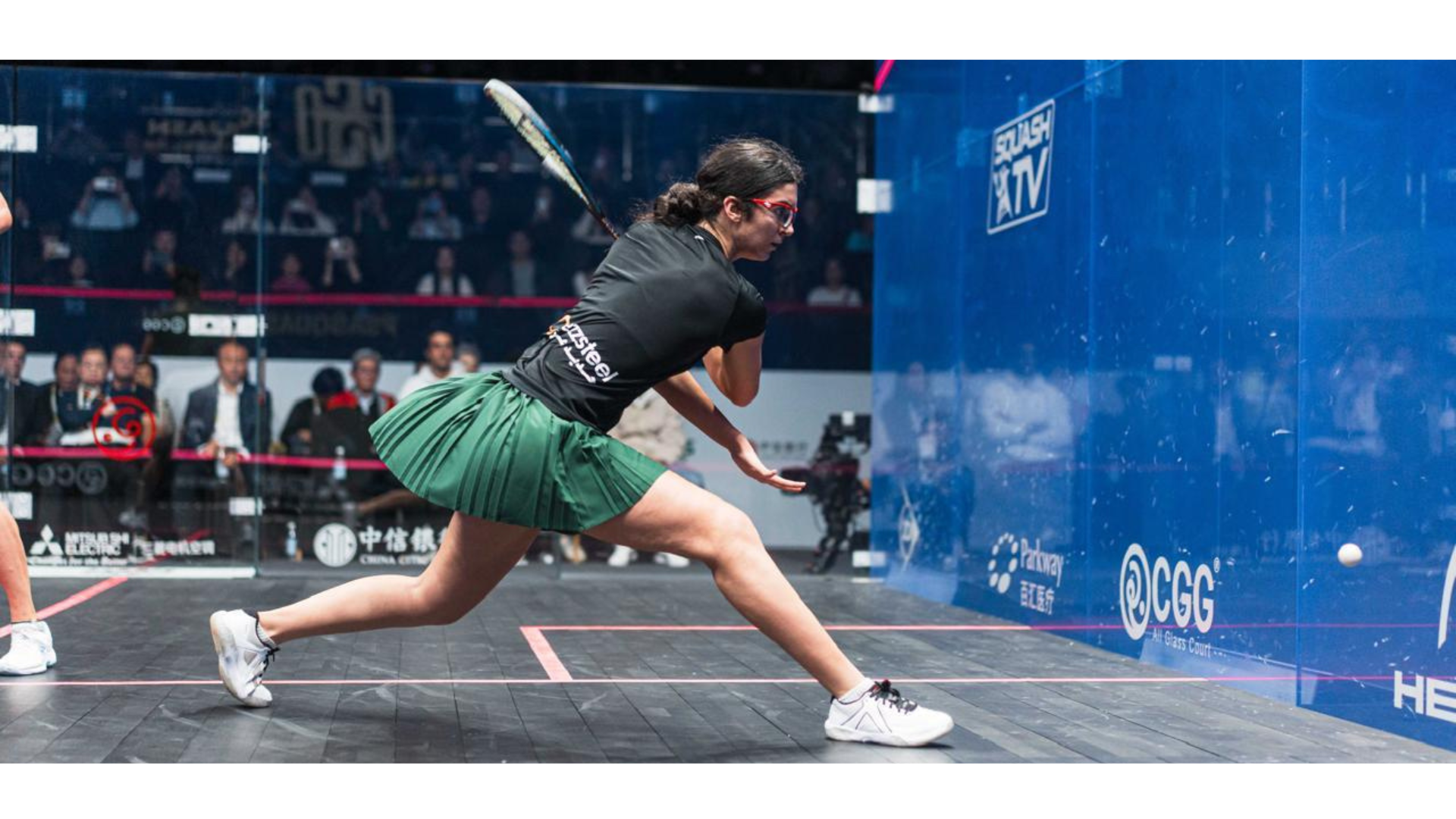 Amina Orfi attacks a squash ball with her racket