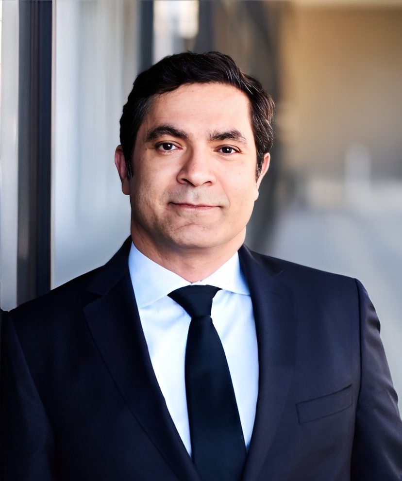 A headshot of a man wearing a suit and tie
