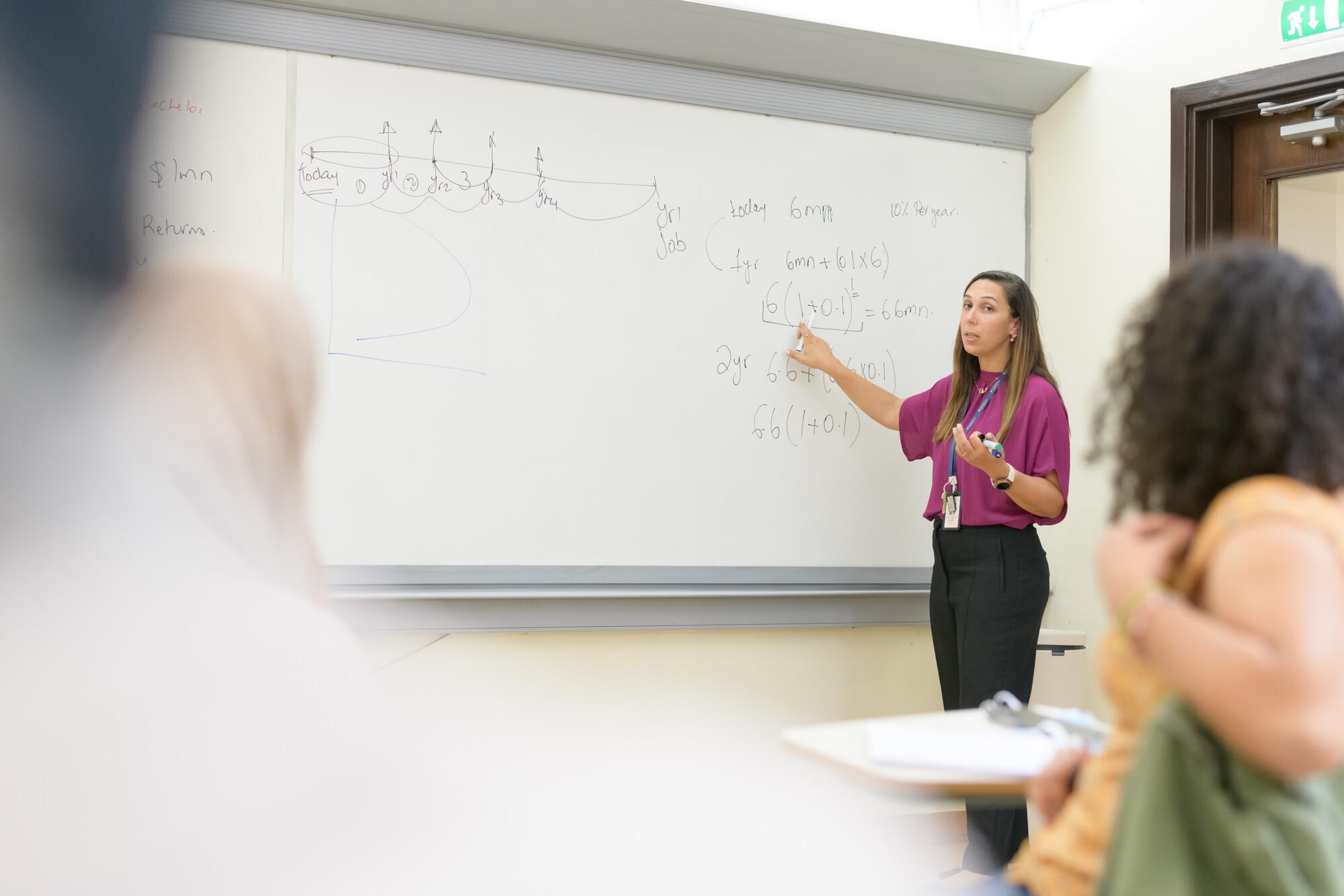 school of business faculty explaining on white board in classroom for students