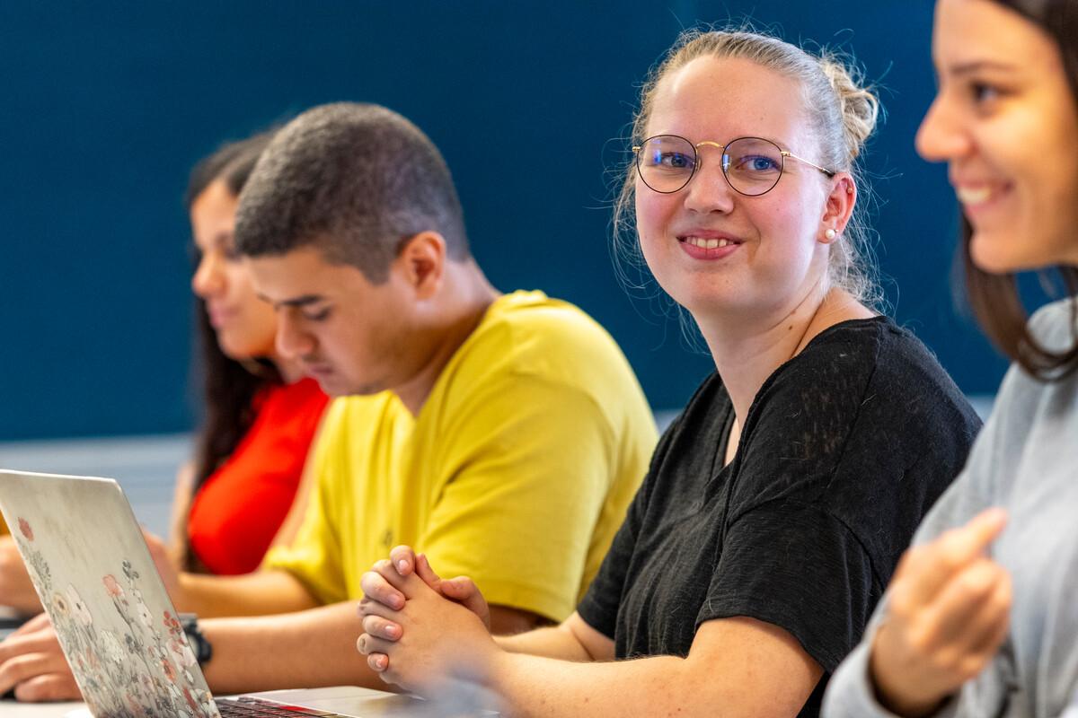 students in class taking notes and smiling