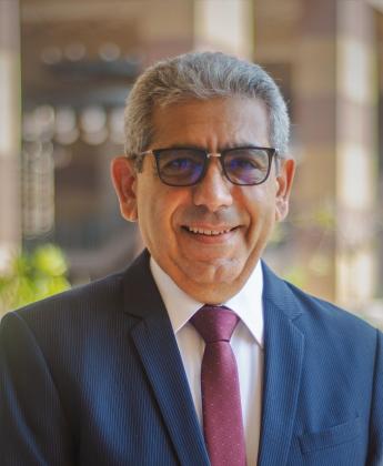 A man is smiling and wearing a suit and glasses
