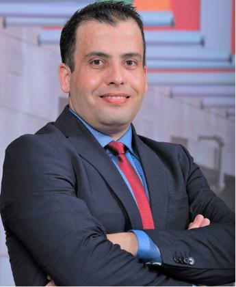 Said Toumi stands in a suit with arms crossed