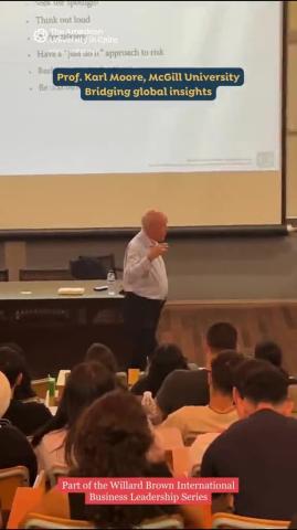 A man is standing in lecture hall in front of an audience