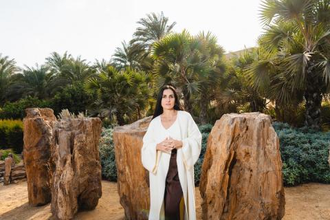 A woman is standing in a garden in front of big rocks