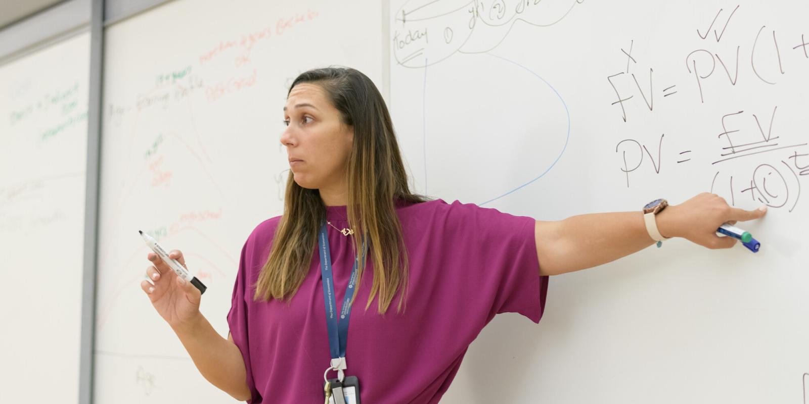 economics professor explaining information on white board in class