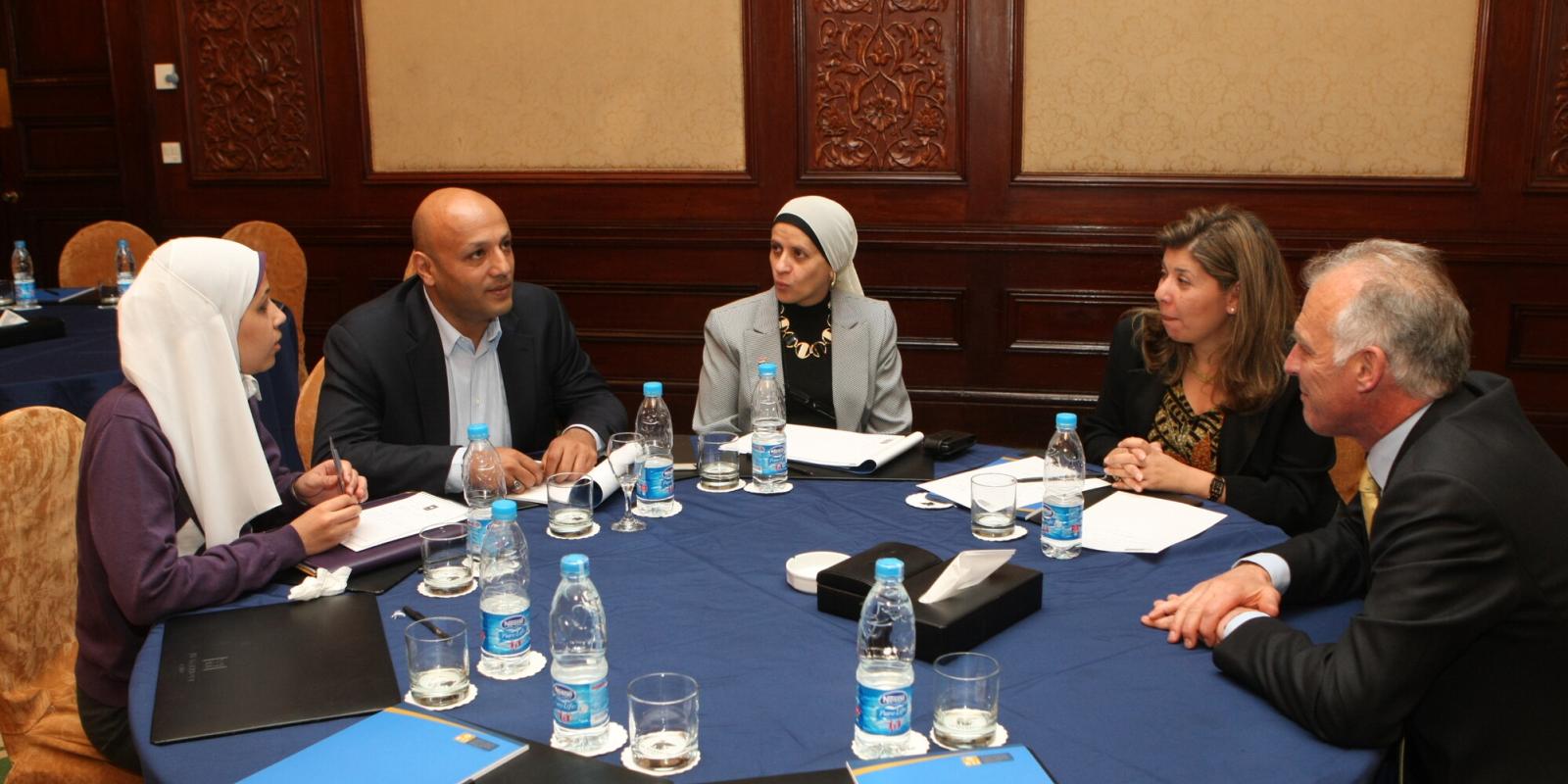 Group of executives sitting on round table discussing issues