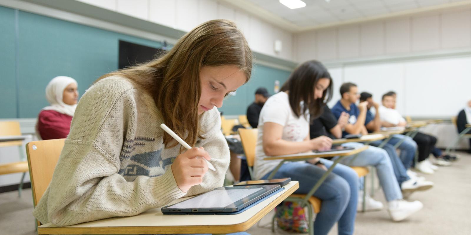 student writing in classroom and taking notes