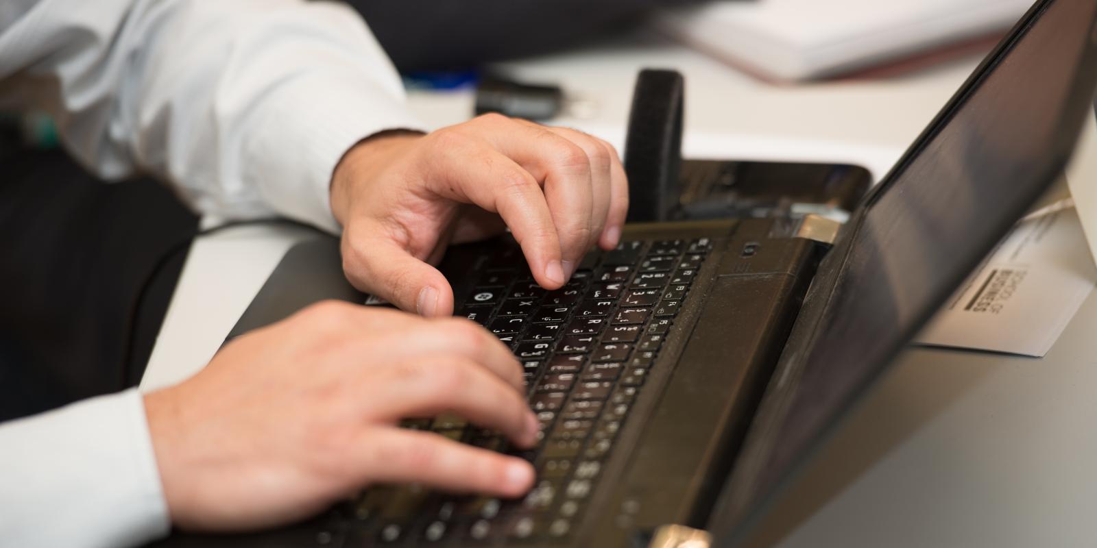 male student typing on the laptop