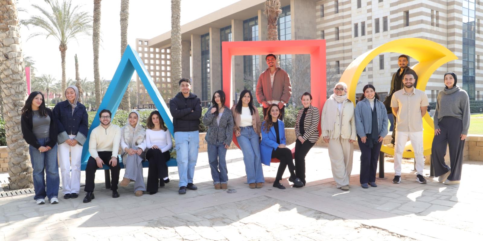 group of students infront of AUC logo in the gardens 