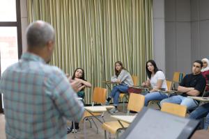 students in classroom looking at professor explaining 