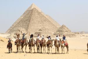 international students on camels at the pyramids taking a touristic tour